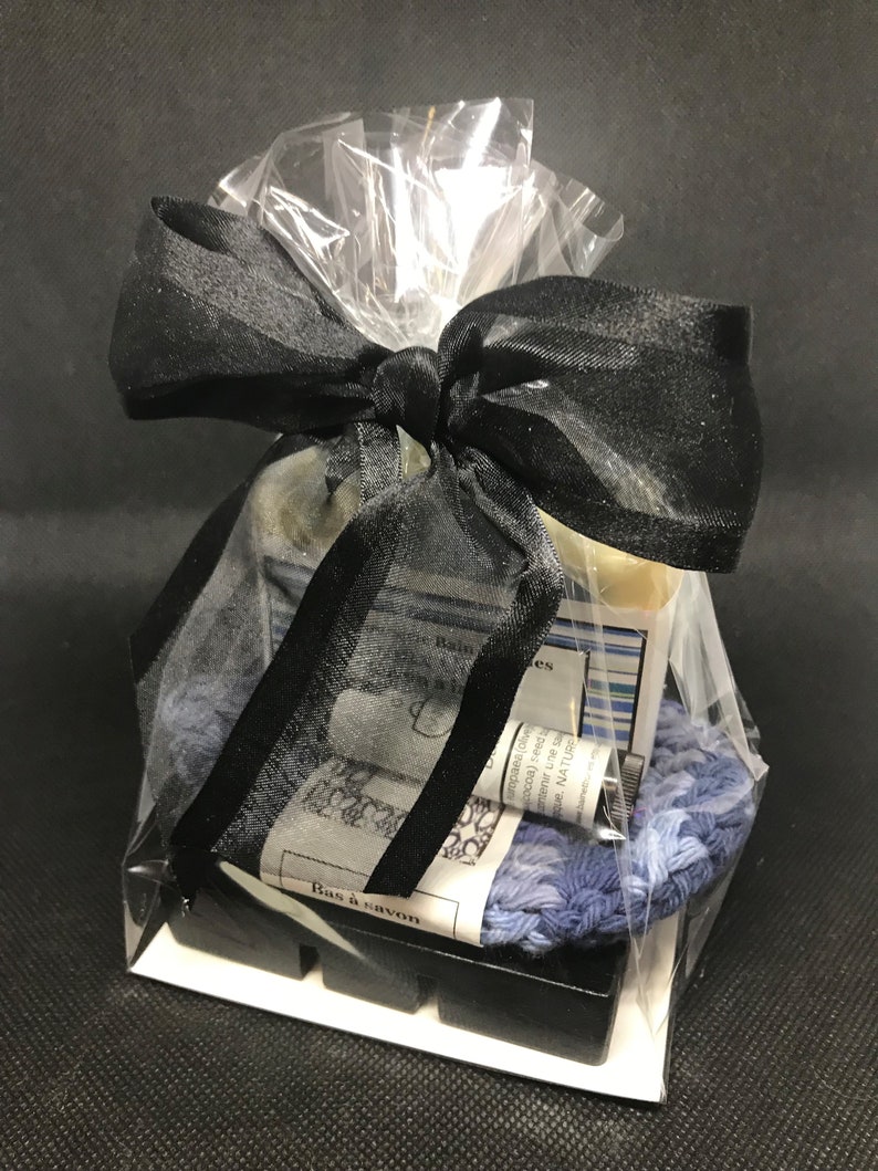 Puede incluir: Un set de regalo con una cinta negra y una bolsa de pl&aacute;stico transparente. El set incluye una pastilla de jab&oacute;n, una peque&ntilde;a botella de aceite esencial, una toallita y una peque&ntilde;a bolsa de sales de ba&ntilde;o. La etiqueta del jab&oacute;n dice "Bas &agrave; savon".