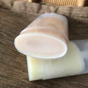 May include: Two clear plastic deodorant containers with white deodorant inside. The containers are stacked on top of each other.