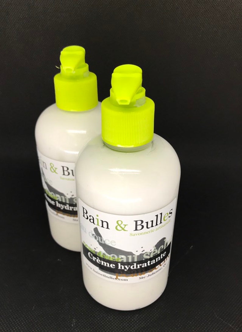 Może przedstawiać: Dwie białe plastikowe butelki z zielonymi pompkami i czarnymi etykietami. Etykiety zawierają napis "Bain & Bulles Savonnerie artisanale" i "Cr&egrave;me hydratante".