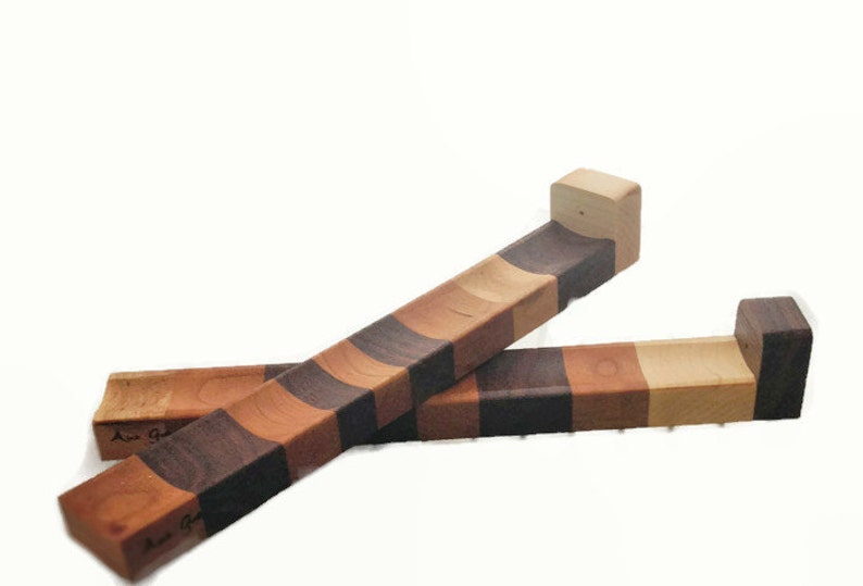 Puede incluir: Dos soportes de tabla de cortar de madera con un patr&oacute;n a rayas de madera de cerezo, arce y nogal. Los soportes est&aacute;n dise&ntilde;ados para colgar en la pared.