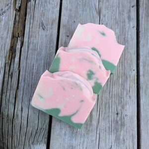 Op de afbeelding: Drie handgemaakte zeepjes met een roze en groene swirl-patroon. De zeepjes zijn op elkaar gestapeld.