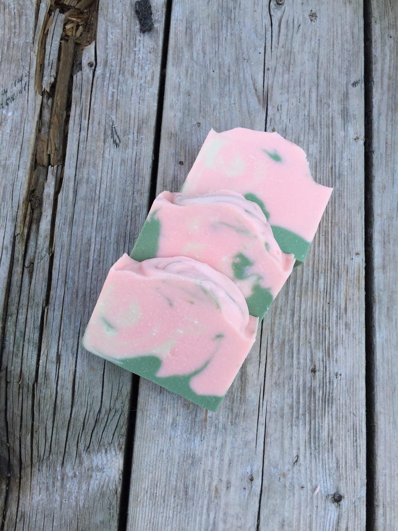 Op de afbeelding: Drie handgemaakte zeepjes met een roze en groene swirl-patroon. De zeepjes zijn op elkaar gestapeld.