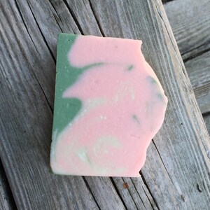 Op de afbeelding: Een handgemaakte zeep met een swirl-ontwerp in roze en groene tinten.