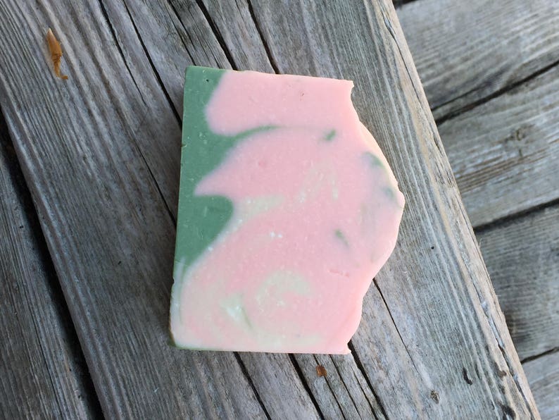 Op de afbeelding: Een handgemaakte zeep met een swirl-ontwerp in roze en groene tinten.