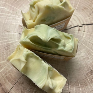 May include: Three bars of handmade soap with a swirl design. The soap is white with green swirls and has a label that says "Lavender & Butter" and "Rosemary & Mint".