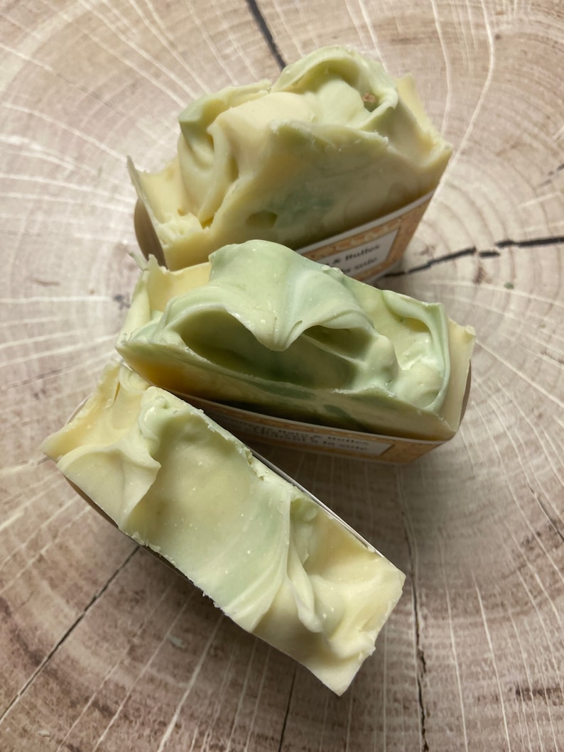 May include: Three bars of handmade soap with a swirl design. The soap is white with green swirls and has a label that says "Lavender & Butter" and "Rosemary & Mint".