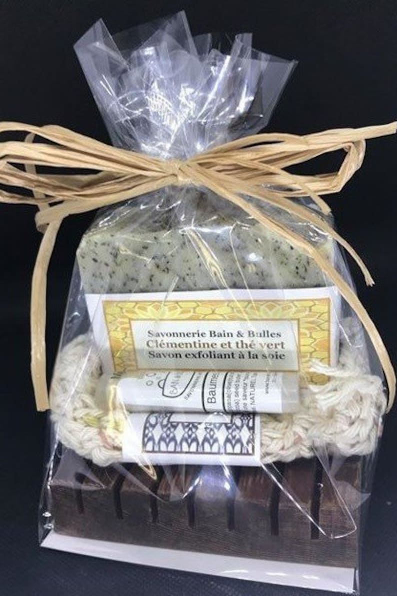 Puede incluir: Un set de regalo que contiene una barra de jab&oacute;n verde, una peque&ntilde;a botella de b&aacute;lsamo, una esponja natural de luffa y un jabonera de madera. El jab&oacute;n est&aacute; etiquetado con "Savonnerie Bain & Bulles Cl&eacute;mentine et th&eacute; vert Savon exfoliant &agrave; la soie".