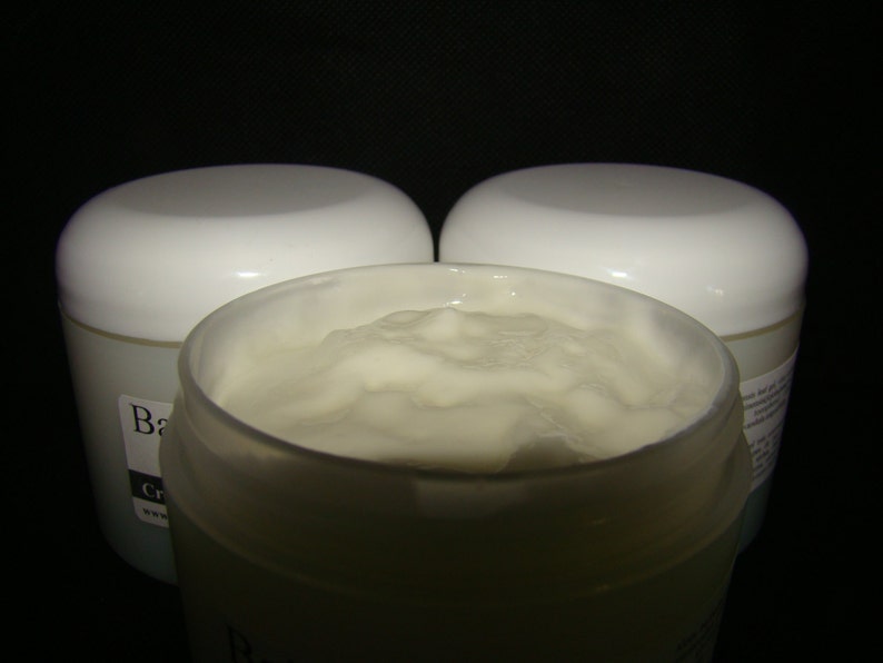 May include: Three white jars of body butter, two are closed and one is open, showing the white, creamy texture of the product.
