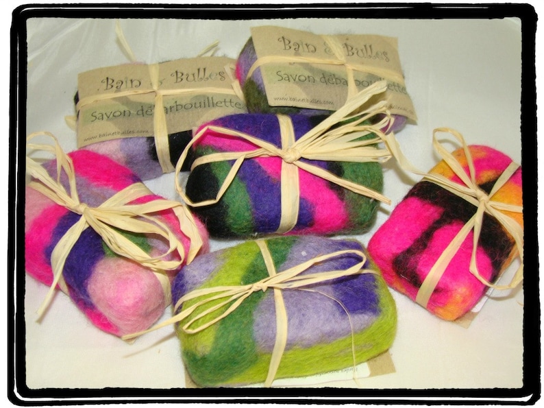 May include: Four colorful felted soap bars wrapped in natural twine. Each bar has a different pattern of pink, purple, green, and black wool. The bars are labeled "Bain de Bulles" and "Savon de la Bourbouillette".