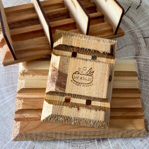 Puede incluir: Jabonera de madera con un dise&ntilde;o en relieve y un logotipo que dice "Bar & Bolles, Exquisite Originals".