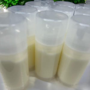 May include: A collection of cylindrical plastic pump bottles filled with an opaque off-white cream. Each bottle features a clear, removable cap that covers the pump mechanism, creating a uniform appearance across the group of containers.