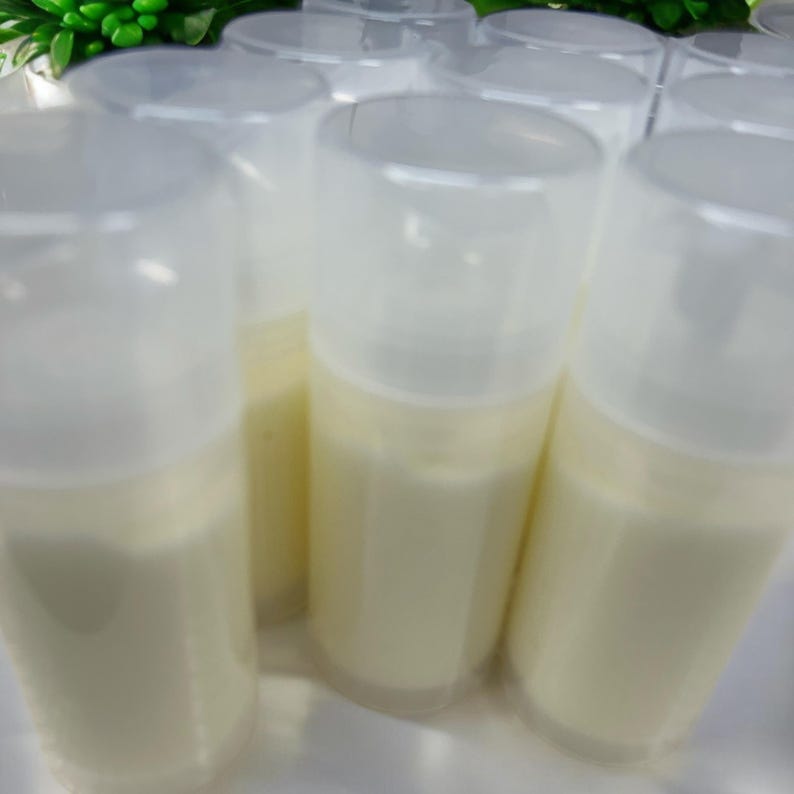 May include: A collection of cylindrical plastic pump bottles filled with an opaque off-white cream. Each bottle features a clear, removable cap that covers the pump mechanism, creating a uniform appearance across the group of containers.