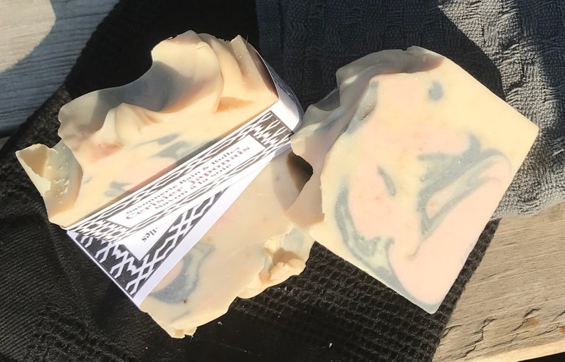 Puede incluir: Dos pastillas de jab&oacute;n rectangulares hechas a mano con un patr&oacute;n jaspeado en tonos crema, rosa suave y gris carb&oacute;n. Una etiqueta de papel blanco con bordes geom&eacute;tricos negros y el texto Savonnerie Bain & Bulles Cerisier Japonais envuelve el jab&oacute;n.