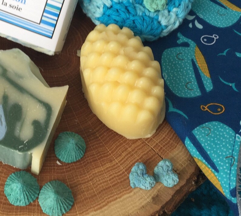 May include: A yellow, textured soap bar on a wooden surface with blue and white decorative items.