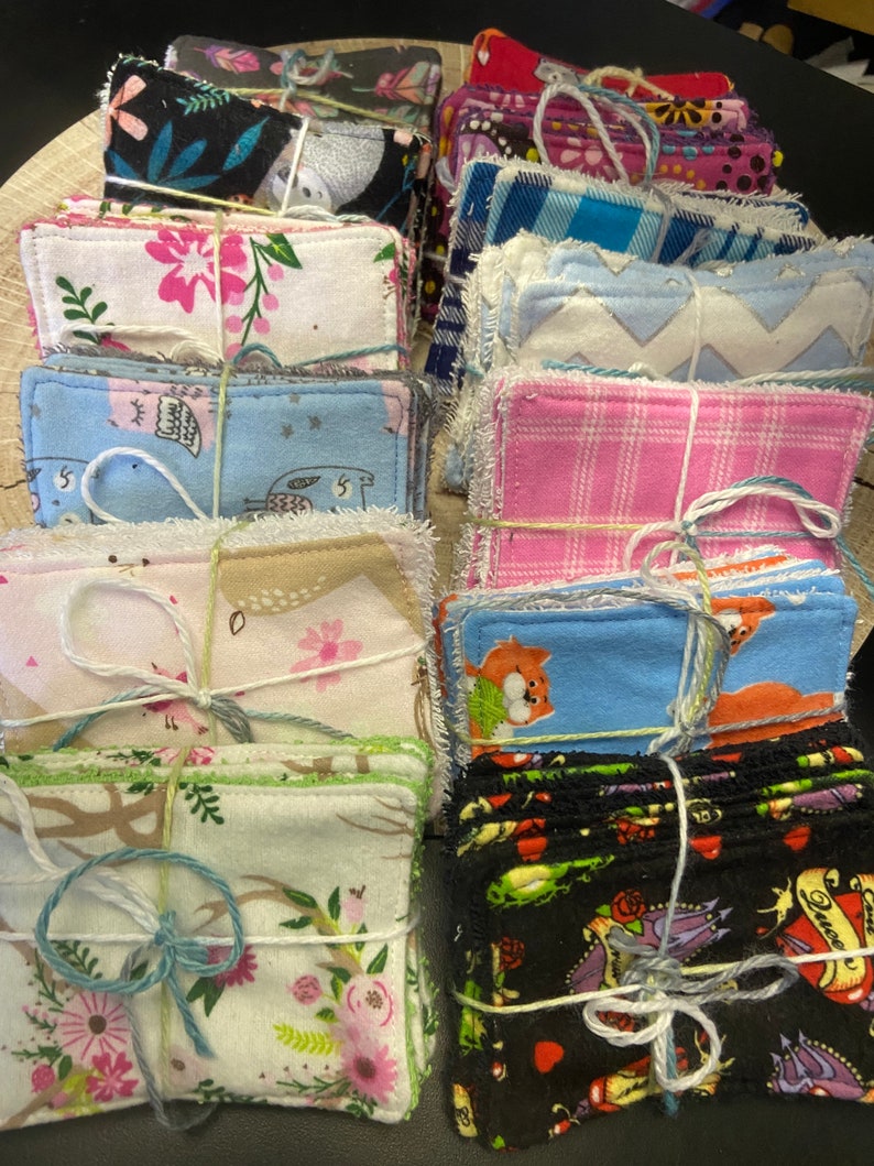 Op de afbeelding: Een verzameling handgemaakte herbruikbare make-up remover pads. De pads zijn gemaakt van verschillende stoffen en hebben verschillende patronen, waaronder bloemen-, geometrische en dierenprints. De pads zijn met touw aan elkaar gebonden.