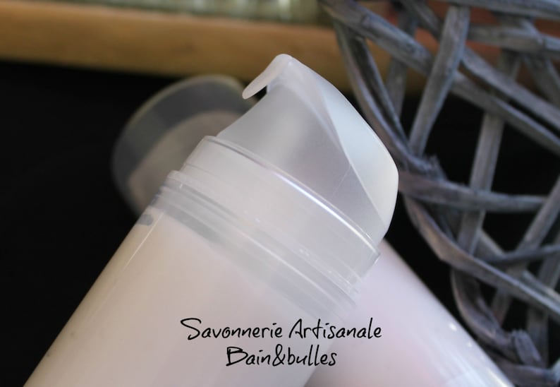 May include: A white cylindrical cosmetic pump bottle with a translucent cap. The bottle features black printed text that reads Savonnerie Artisanale Bain&bulles. The pump mechanism is made of a semi-transparent white plastic material.