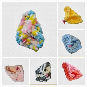 May include: Assortment of colourful crocheted hair scrunchies in various colours, including pink, blue, yellow, grey, and black. Each scrunchie features a small pink flower charm.