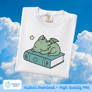May include: White t-shirt featuring a cartoon illustration of a sleeping green dragon on a teal book with a gold star. The shirt has a crew neck and a tag that says "Comfort Colors". The bottom of the image says "Instant Download ~ High Quality PNG".