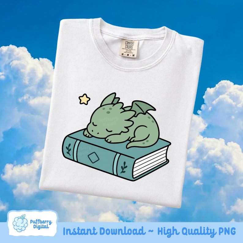 May include: White t-shirt featuring a cartoon illustration of a sleeping green dragon on a teal book with a gold star. The shirt has a crew neck and a tag that says "Comfort Colors". The bottom of the image says "Instant Download ~ High Quality PNG".