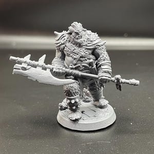 May include: A gray plastic miniature figurine of a furry, humanoid creature holding a large axe. The creature has a fierce expression and is wearing armor and a cloak. The figurine is standing on a round base.