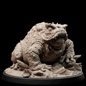 Könnte beinhalten: Eine detaillierte, handbemalte Miniatur eines grotesken, krötenartigen Wesens mit einem großen Maul und ausdrucksstarken Augen. Die Miniatur ist auf einem felsigen Sockel platziert, mit einem Baumstamm und anderen Trümmern, die um sie herum verstreut sind.