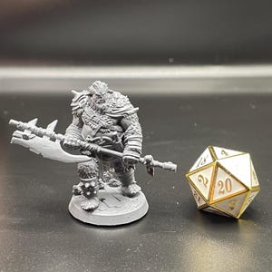 May include: A gray plastic miniature figurine of a warrior holding a large axe. The figurine is standing on a round base. A white 20-sided die with gold accents is in the background.