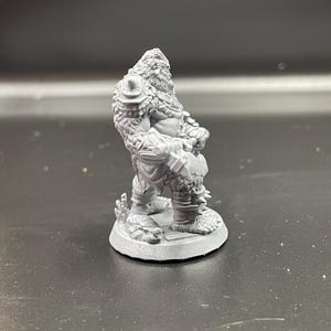 May include: A gray plastic miniature figurine of a furry, humanoid creature holding a weapon. The figure is standing on a round base.