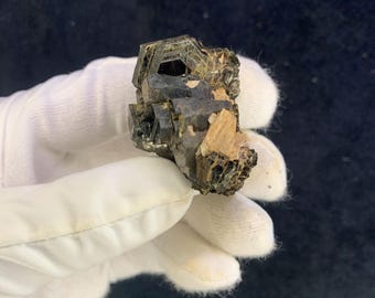 May include: A cluster of dark brown and green crystals with a geometric shape. The crystals are arranged in a cluster and have a rough, natural texture.
