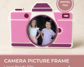 May include: A camera-shaped picture frame featuring a three-layer design in shades of pink and dark purple. The circular center holds a photograph of two children. A circular badge in the top right corner contains the text DIGITAL FILE.