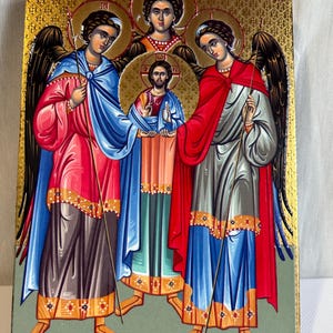 May include: A religious icon depicting three angels with wings, each holding a staff, surrounding a central figure of Jesus Christ. The icon has a gold background with a textured pattern and the text "IS CYNAGIC IN AXXEIES" at the top.