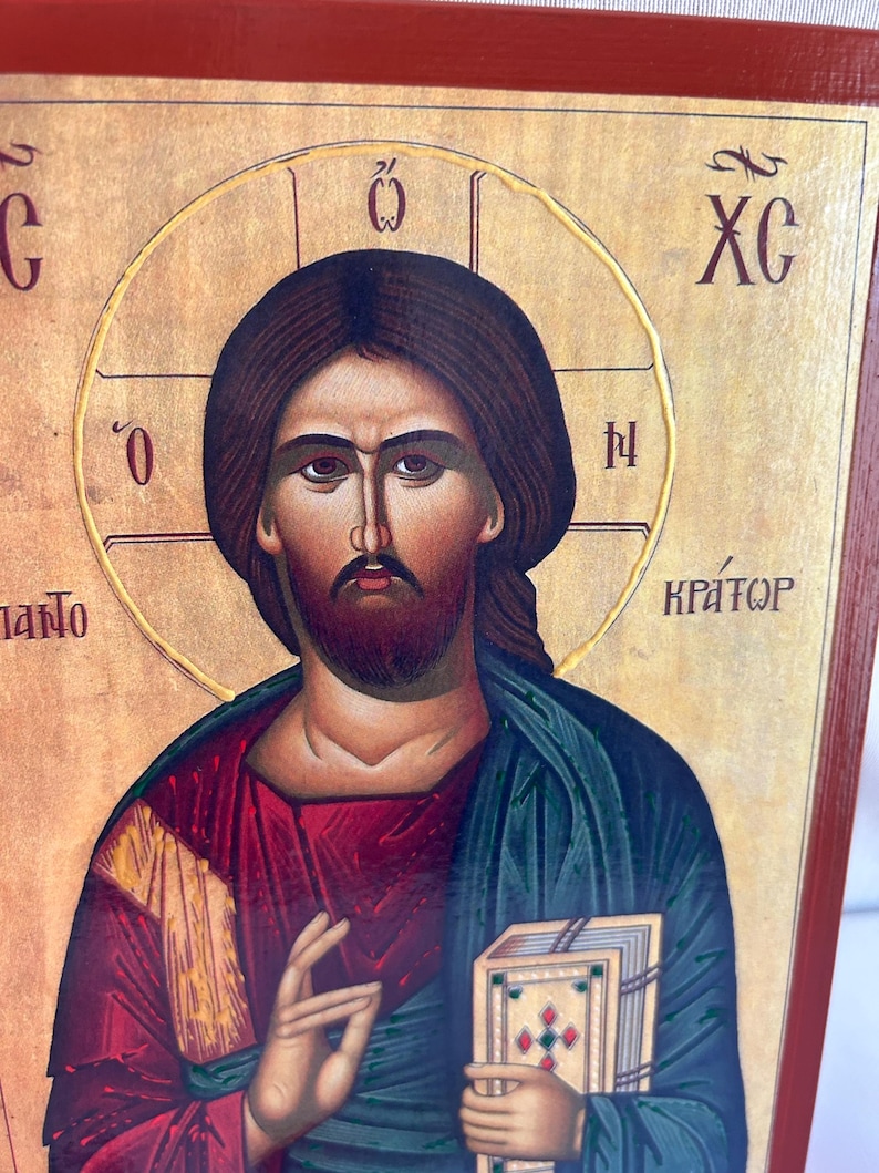 Może przedstawiać: Ikona religijna przedstawiająca Jezusa Chrystusa trzymającego książkę. Ikona jest namalowana w tradycyjnym stylu ze złotymi akcentami i czerwonym tłem. Tekst "XC" jest widoczny w prawym g&oacute;rnym rogu ikony.