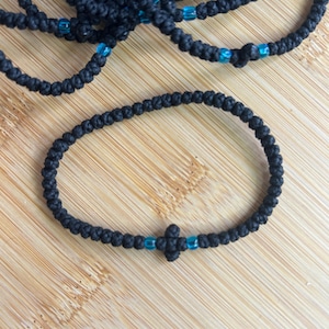 May include: A black knotted prayer rope with blue beads and a black cross charm.