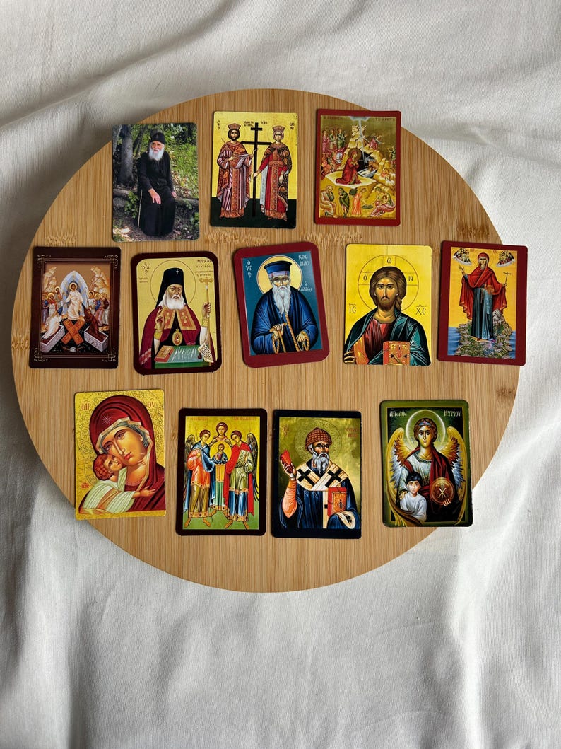 May include: A collection of religious icons featuring various saints and biblical scenes. The icons are rectangular with gold, red, and blue accents, arranged on a round wooden surface. The images depict figures in traditional attire.