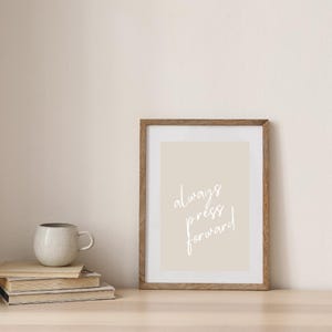May include: A framed print with a beige background and white text that reads "always press forward".