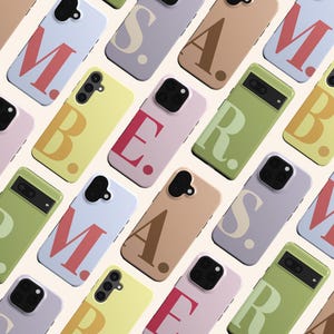May include: An assortment of mobile phone cases in pastel shades, each displaying a bold letter in a contrasting hue. The cases are arranged in a repeating pattern, highlighting different designs and phone models.