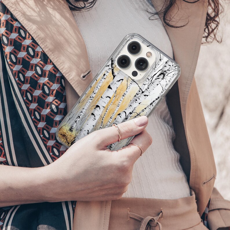 Puede incluir: Una funda transparente para tel&eacute;fono con un dise&ntilde;o de &aacute;rbol de abedul blanco. La funda tiene una protuberancia de c&aacute;mara elevada y una parte posterior transparente.