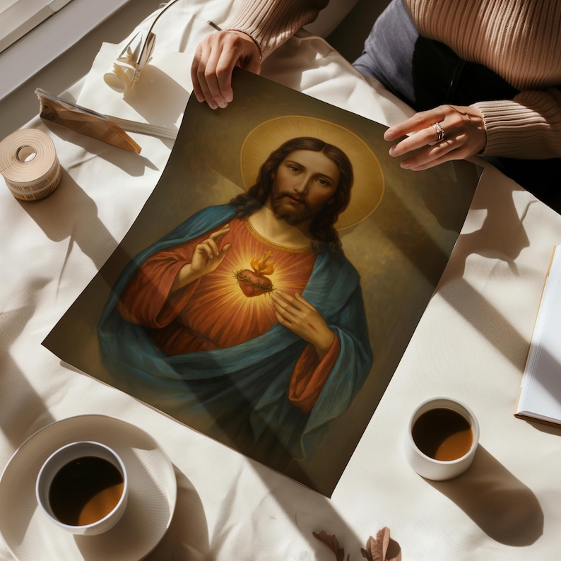 May include: A print of a religious painting depicting Jesus with a halo, wearing a red and blue robe. The image features a glowing heart with flames. The artwork is held by a person.