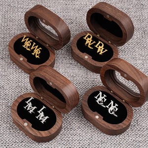 May include: Several wooden jewelry boxes with open lids, each revealing a pair of initial earrings. The earrings are in gold and silver, with the initials WRWR, DW DW, LMLM, and NCNC displayed against a black velvet interior.
