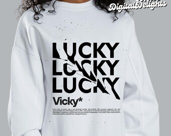 May include: White sweatshirt featuring a black graphic design that reads "LUCKY" three times in a broken, layered style. The text "Vicky*" is below the graphic with a short description about being lucky.
