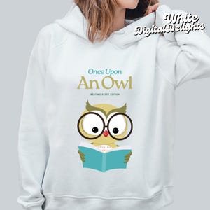 Puede incluir: Una sudadera con capucha azul claro con un gráfico de un búho con gafas leyendo un libro. El texto "Once Upon An Owl" está por encima del búho y el texto "Bedtime Story Edition" está debajo del búho.