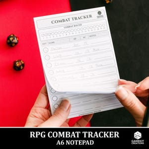 May include: A white A6 notepad with the text "COMBAT TRACKER" and a grid for tracking game information. The notepad is being held by a person. Two dice are visible in the background. The notepad has the text "RPG COMBAT TRACKER A6 NOTEPAD".