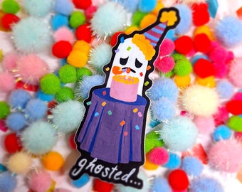 May include: A purple and white sticker featuring a cartoon character wearing a party hat and holding a cake. The character has a sad expression and the text "ghosted..." is below the character.