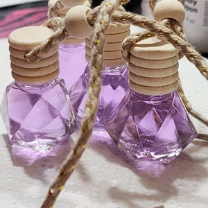 May include: Four purple glass car air fresheners with wooden tops and gold string hanging from them.