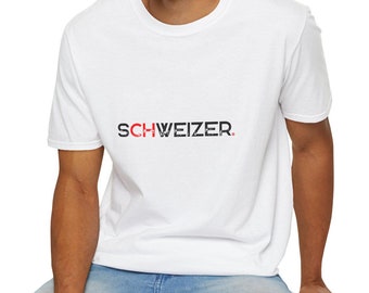 Può includere: T-shirt bianca con la scritta "SCHWEIZER" stampata in nero e rosso. La maglietta è a maniche corte e sembra essere realizzata in un materiale morbido. La persona nell'immagine indossa jeans blu.