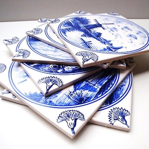 Può includere: Un set di sei piastrelle in ceramica blu e bianca con una scena di mulino a vento olandese. Le piastrelle sono decorate con un motivo floreale blu e bianco.