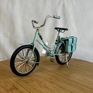 teal blue metal messenger bicycle with two metal messengers bags on the back and silver details