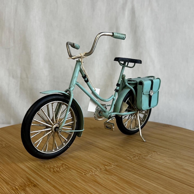 teal blue metal messenger bicycle with two metal messengers bags on the back and silver details
