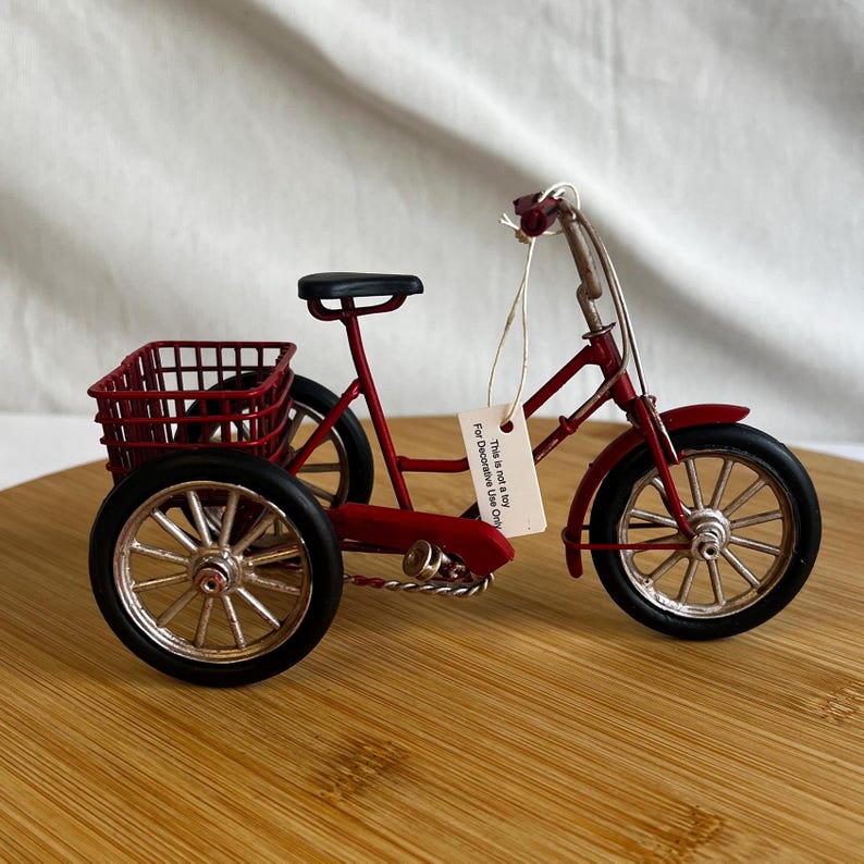a red tricycle bike with a basket at the back