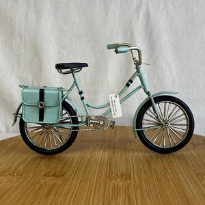 teal blue metal messenger bicycle with two metal messengers bags on the back