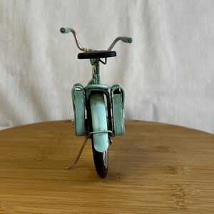 teal blue metal messenger bicycle with two metal messengers bags on the back and silver details